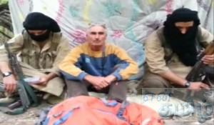 A man who identified himself as Herve Gourdel sits in between two masked gunmen in this still image taken from video